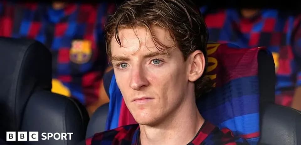 Player seated on bench during match with Barcelona jersey
