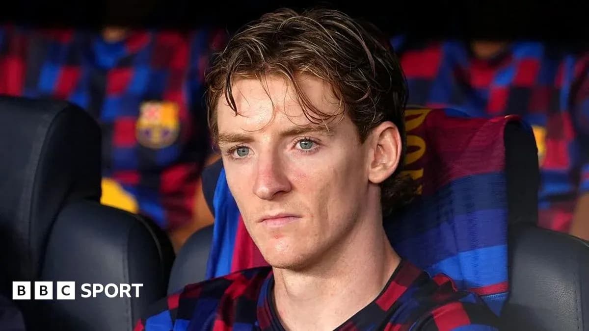 Player seated on bench during match with Barcelona jersey