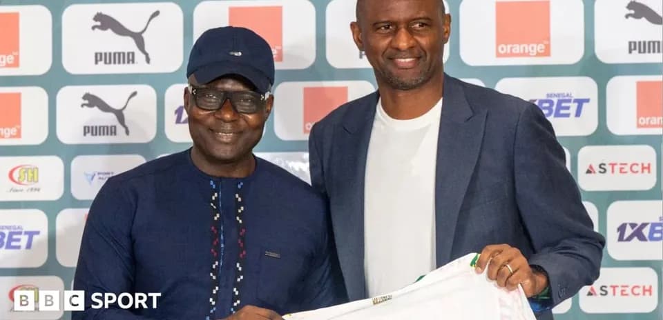 Two men holding a football jersey at press event