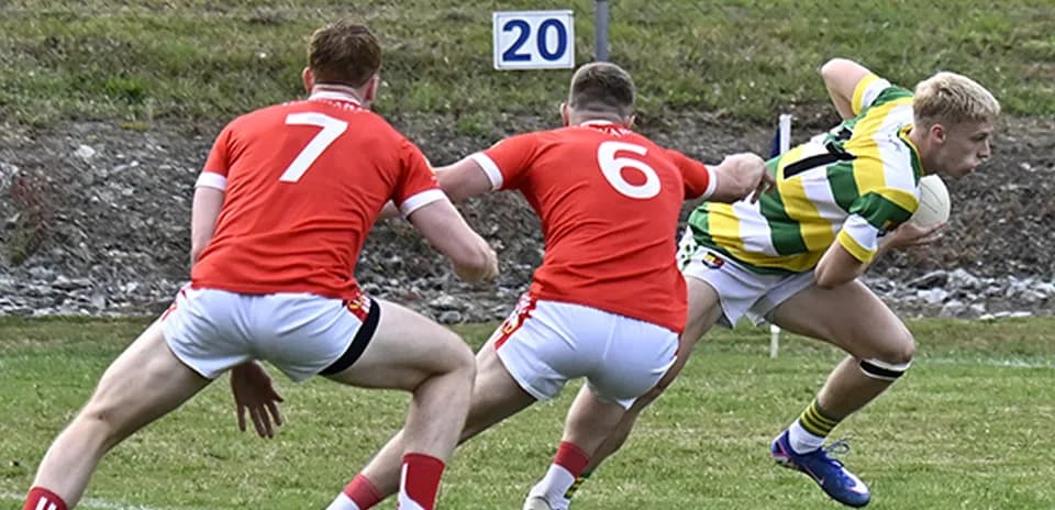 Player in green shirt evading two defenders in red
