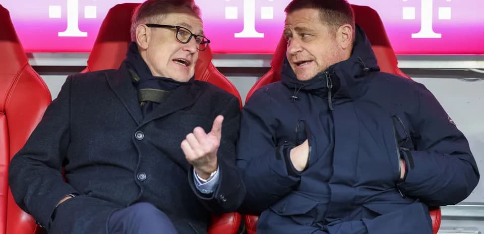 Two officials conversing on the team bench