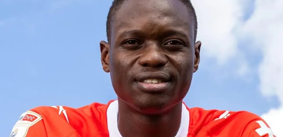 Player in red jersey posing against blue sky