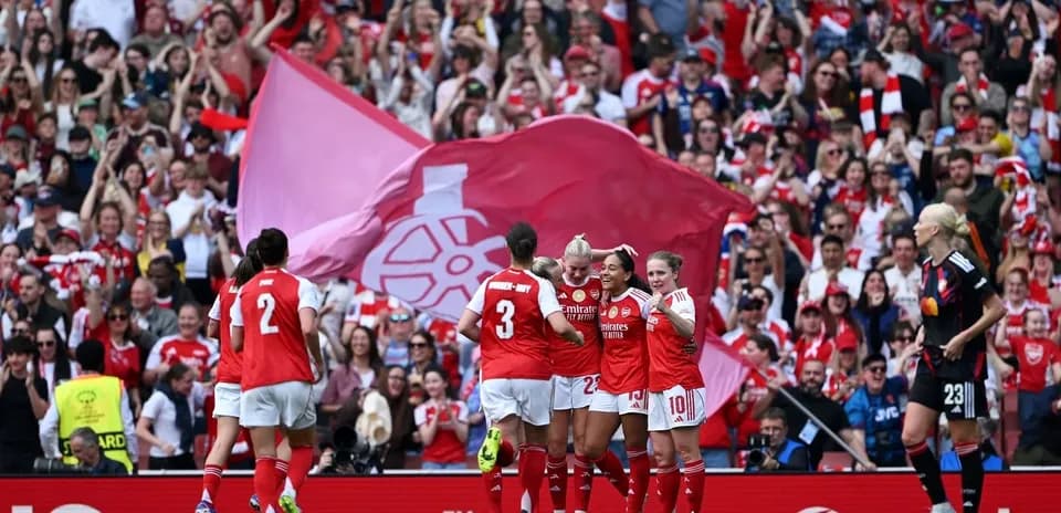 Arsenal players celebrating a goal with fans in background