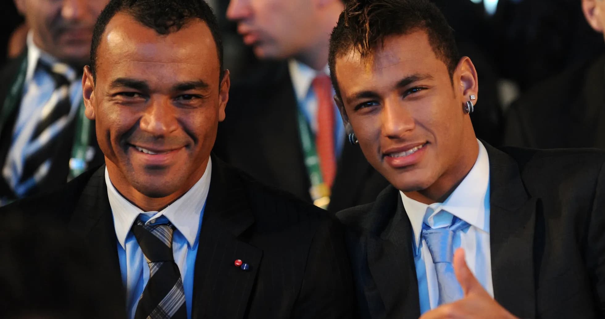 Two men smiling and sitting together at event