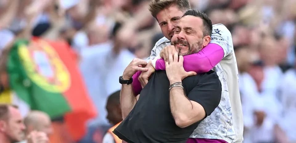 Two coaches celebrating a goal on the sidelines