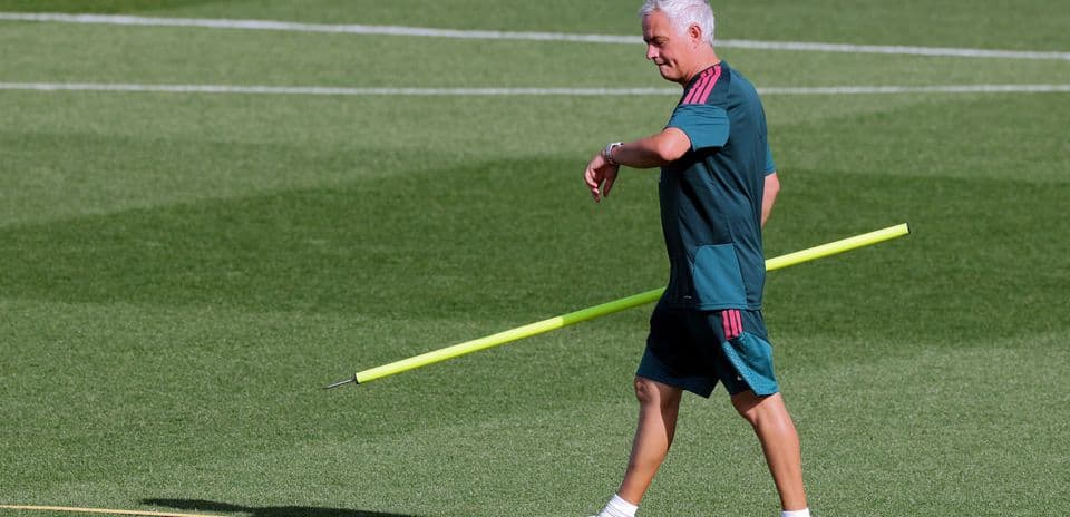 Coach walking with training pole on pitch