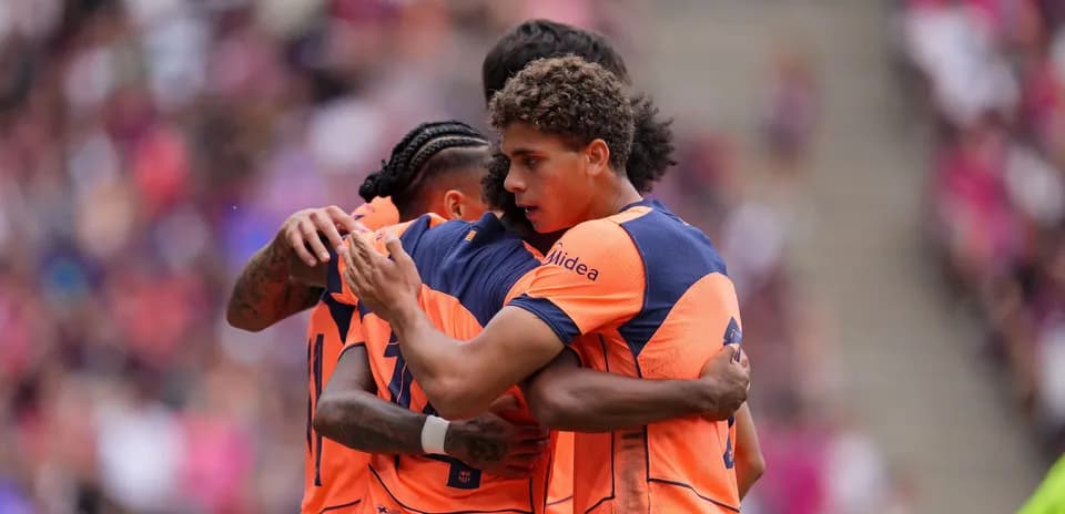 Players celebrating a goal in team uniforms