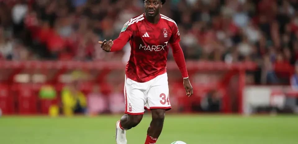 Player in red kit dribbling football on pitch