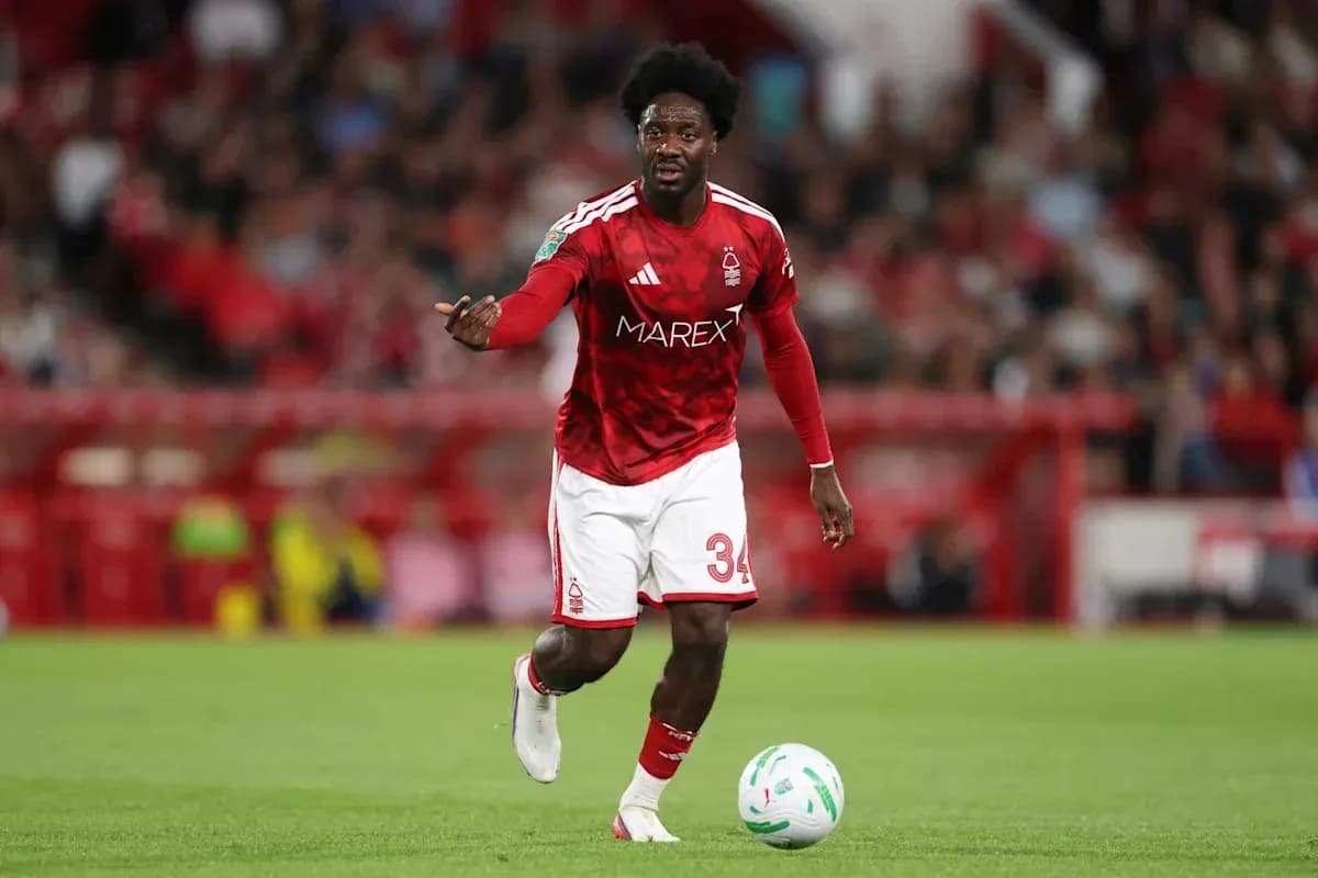 Player in red kit dribbling football on pitch