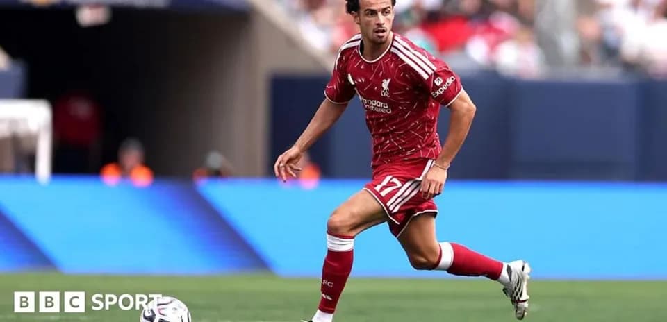 Player in red kit dribbling the ball on field