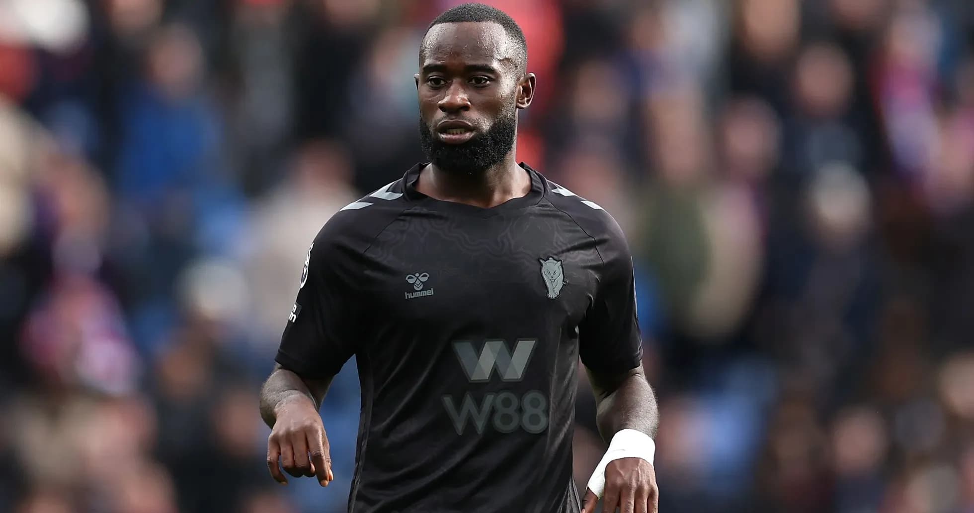 Player in black kit walking on the field