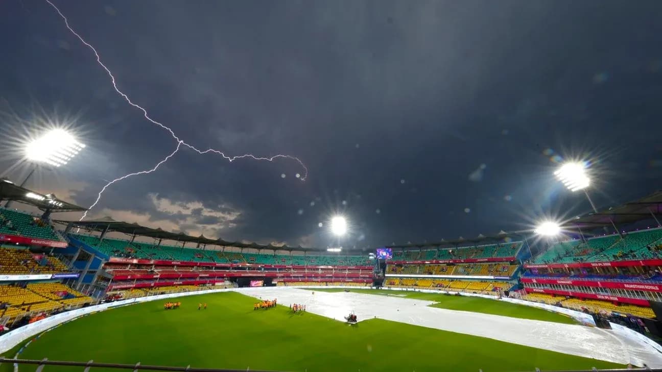 Lightning strikes over a cricket stadium with covers