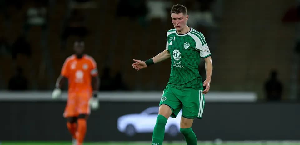 Player in green kit dribbling ball on field