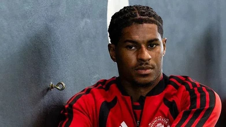 Player in Manchester United training kit posing thoughtfully