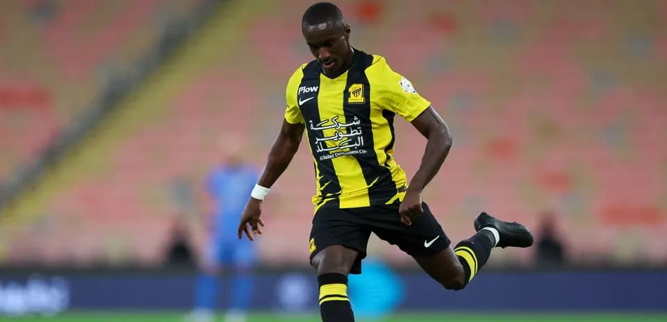 Player in yellow and black kit kicking a soccer ball