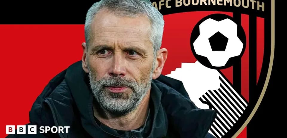 AFC Bournemouth manager in front of club logo