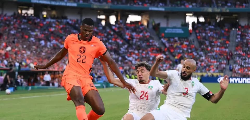 Player 22 from Netherlands evading two Moroccan defenders