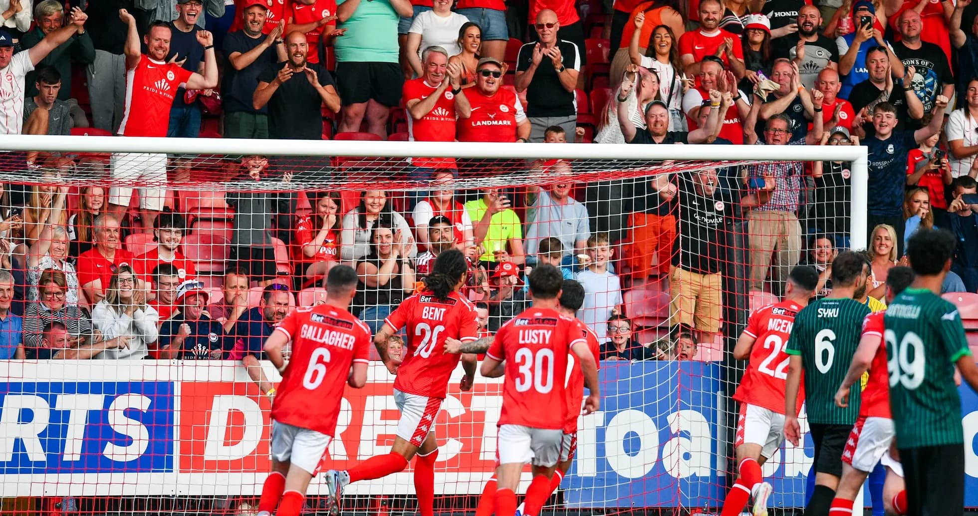 Players celebrating a goal with fans in background