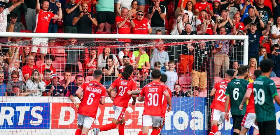Players celebrating a goal with fans in background