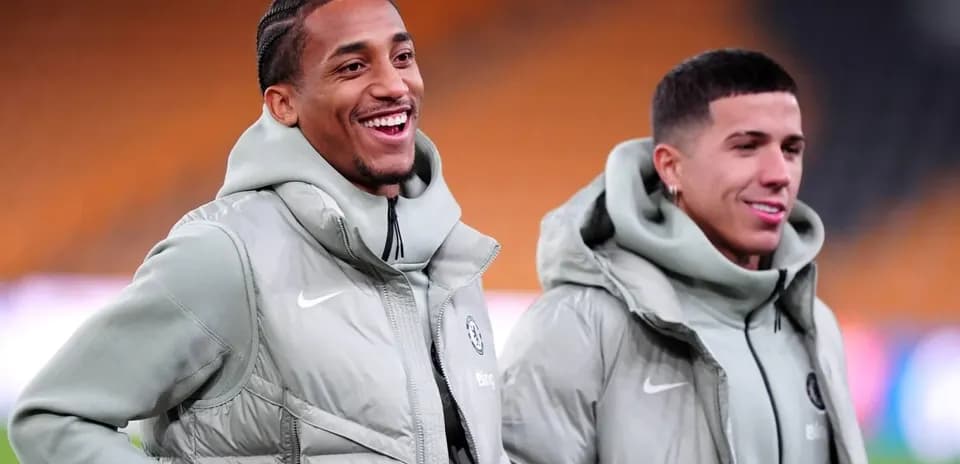 Two players smiling in training jackets on pitch