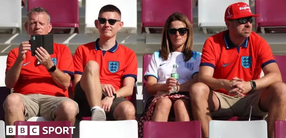 Fans in England jerseys sitting in stadium seats