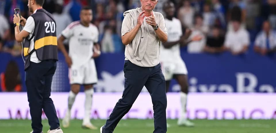 Manager clapping during match with players in background