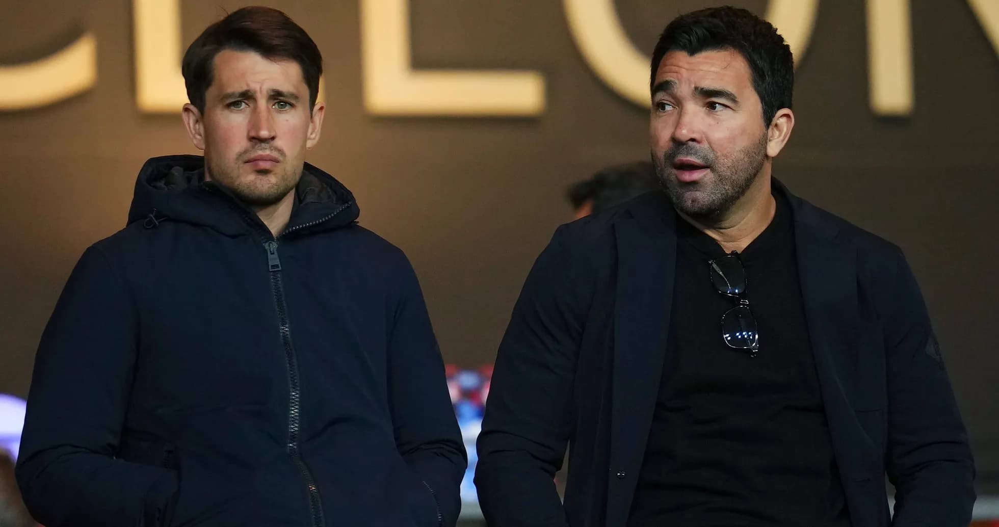 Two men sitting in stadium during a match