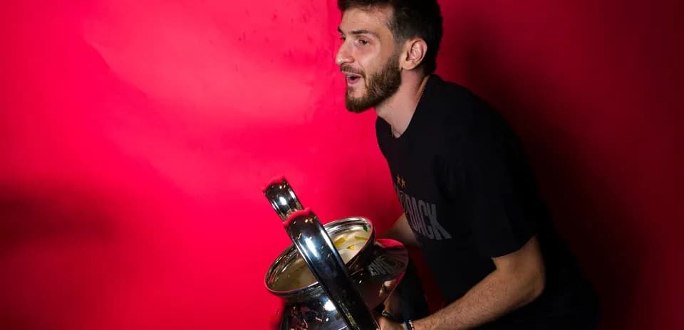 Player holding a trophy against a pink background