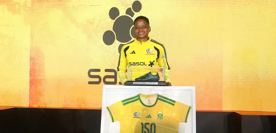 Player holding award with jersey and boot display