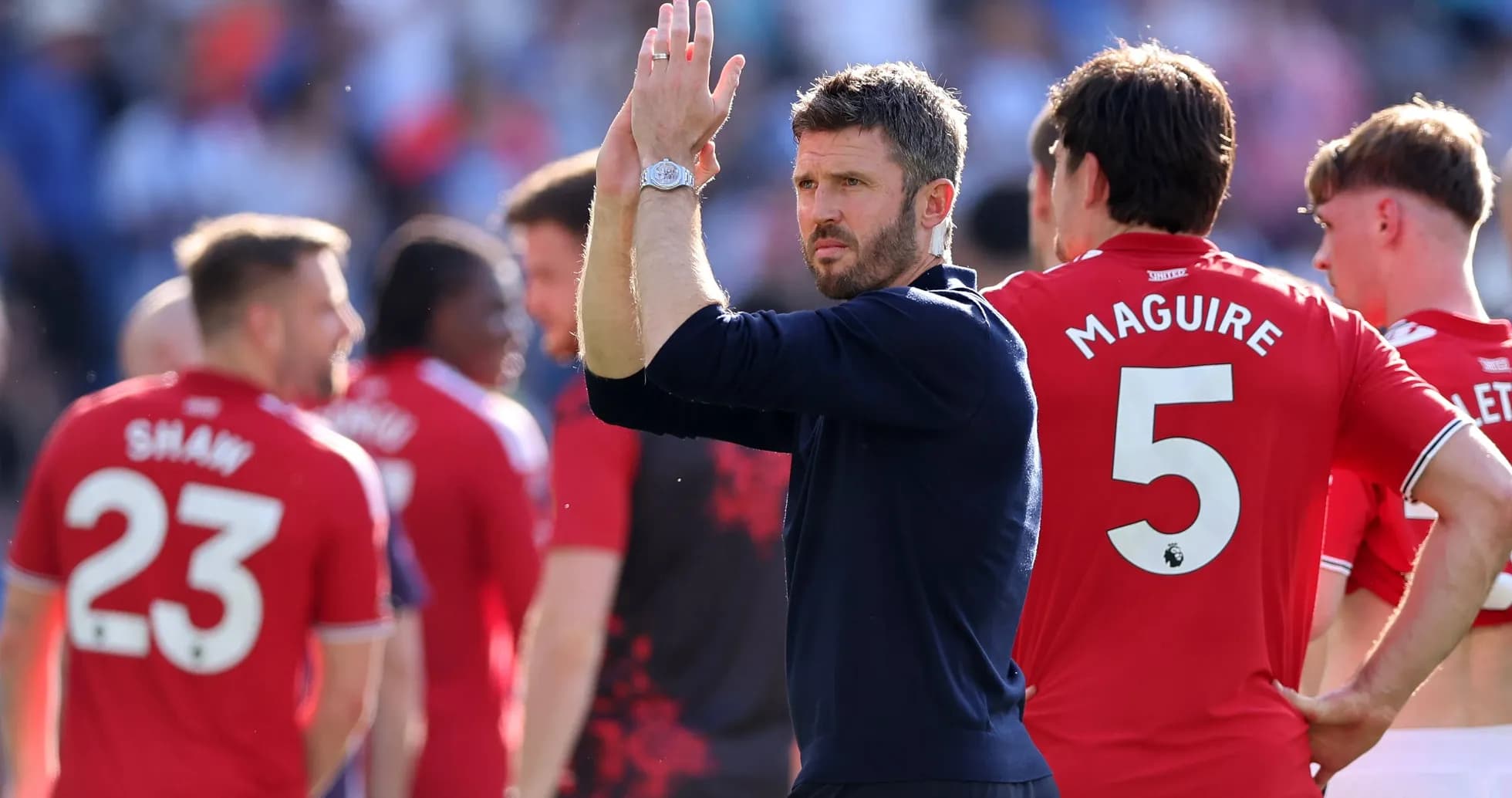 Coach applauding players after match, team in red