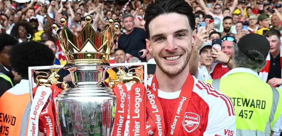 Player holding Premier League trophy with fans celebrating