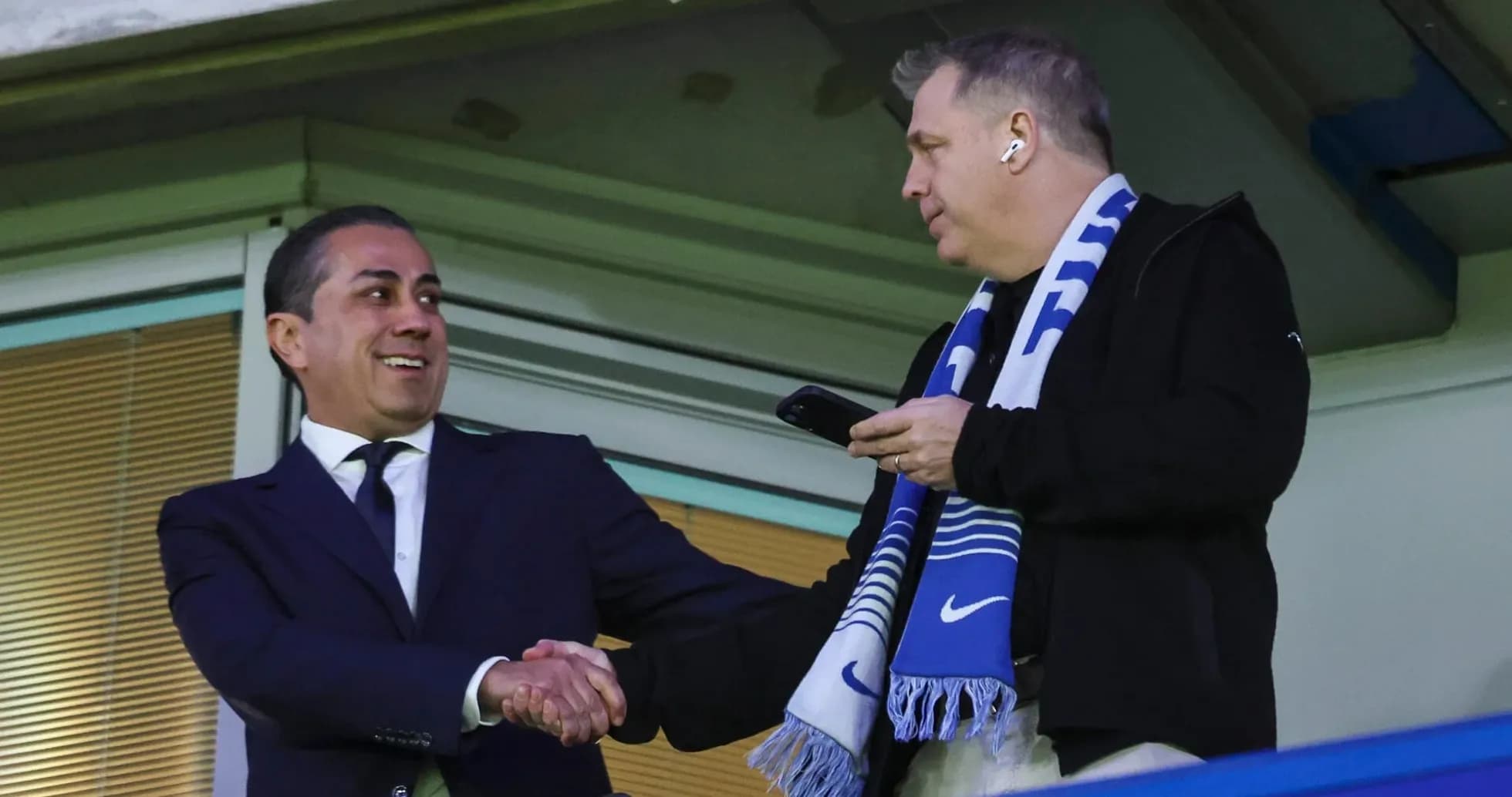 Two men shaking hands in a stadium box