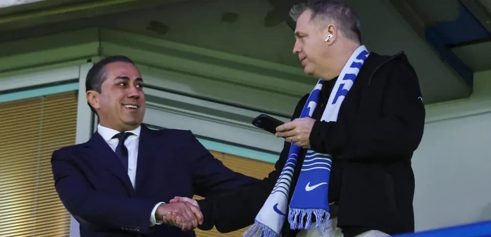 Two men shaking hands in a stadium box