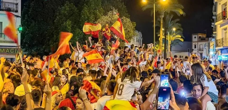 Crowd celebrating at night with Spanish flags