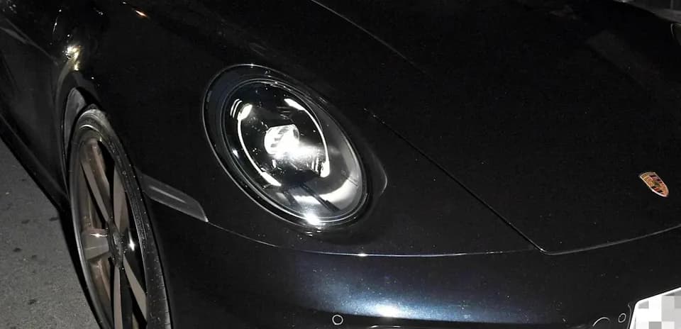 Two men inside a Porsche car at night