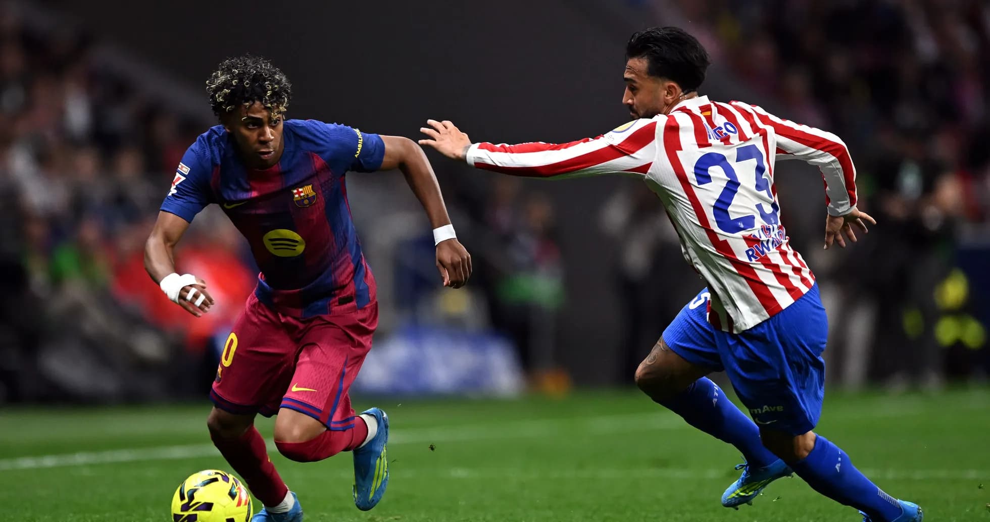 Barcelona player dribbling past Atlético defender