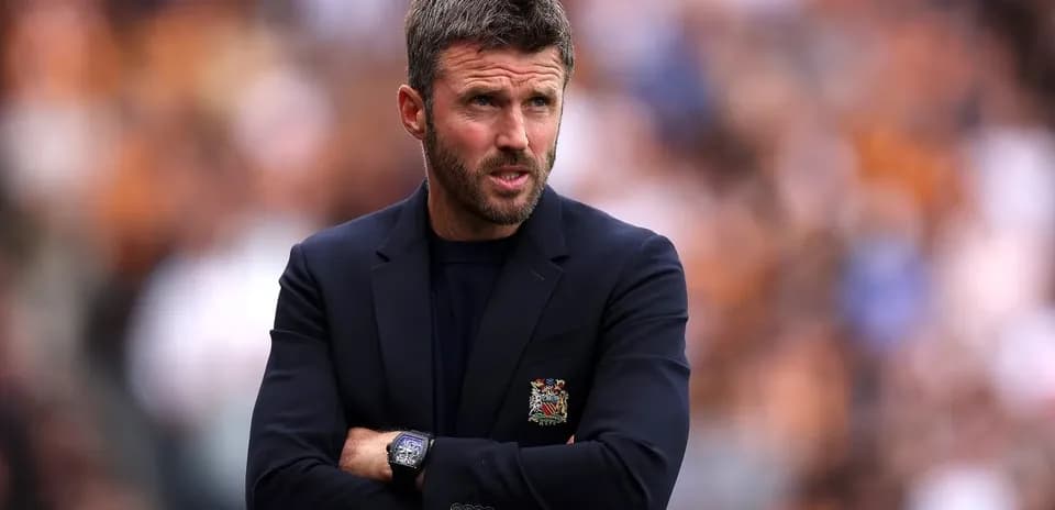 Coach with arms crossed on the sidelines