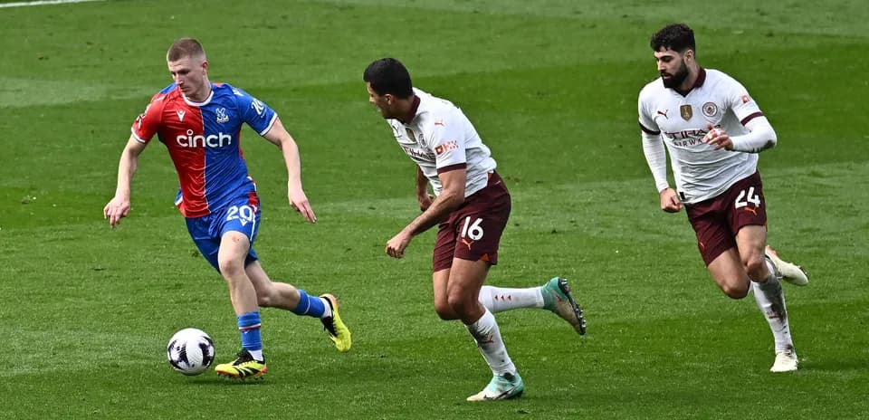 Player in red and blue jersey dribbling ball past defenders