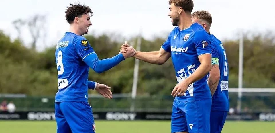 Two players celebrating a goal with a handshake