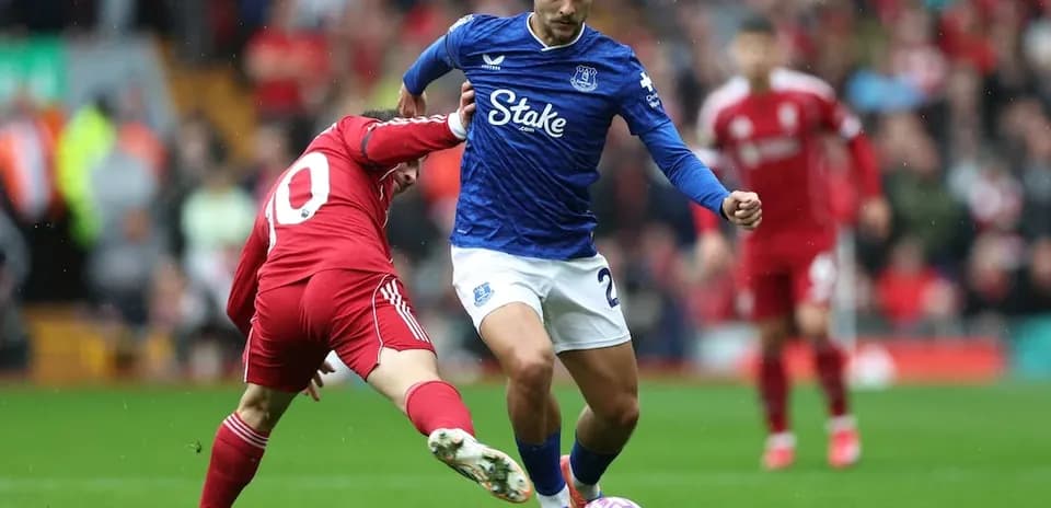 Everton player dribbling past Liverpool opponent