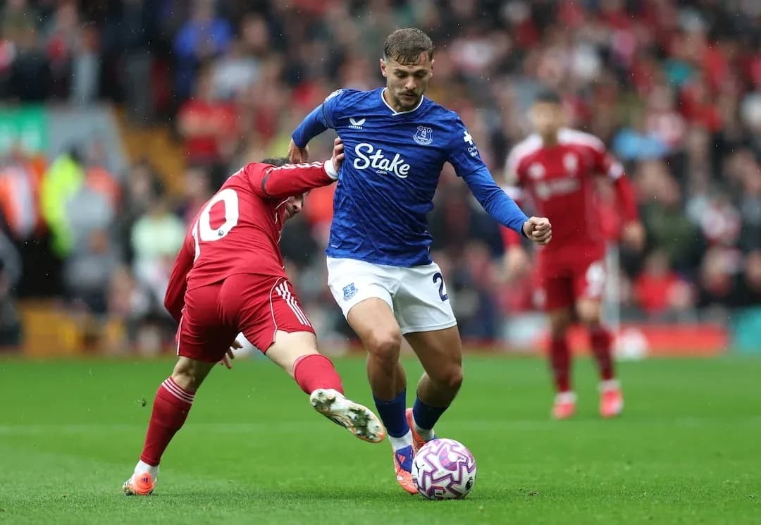 Everton player dribbling past Liverpool opponent