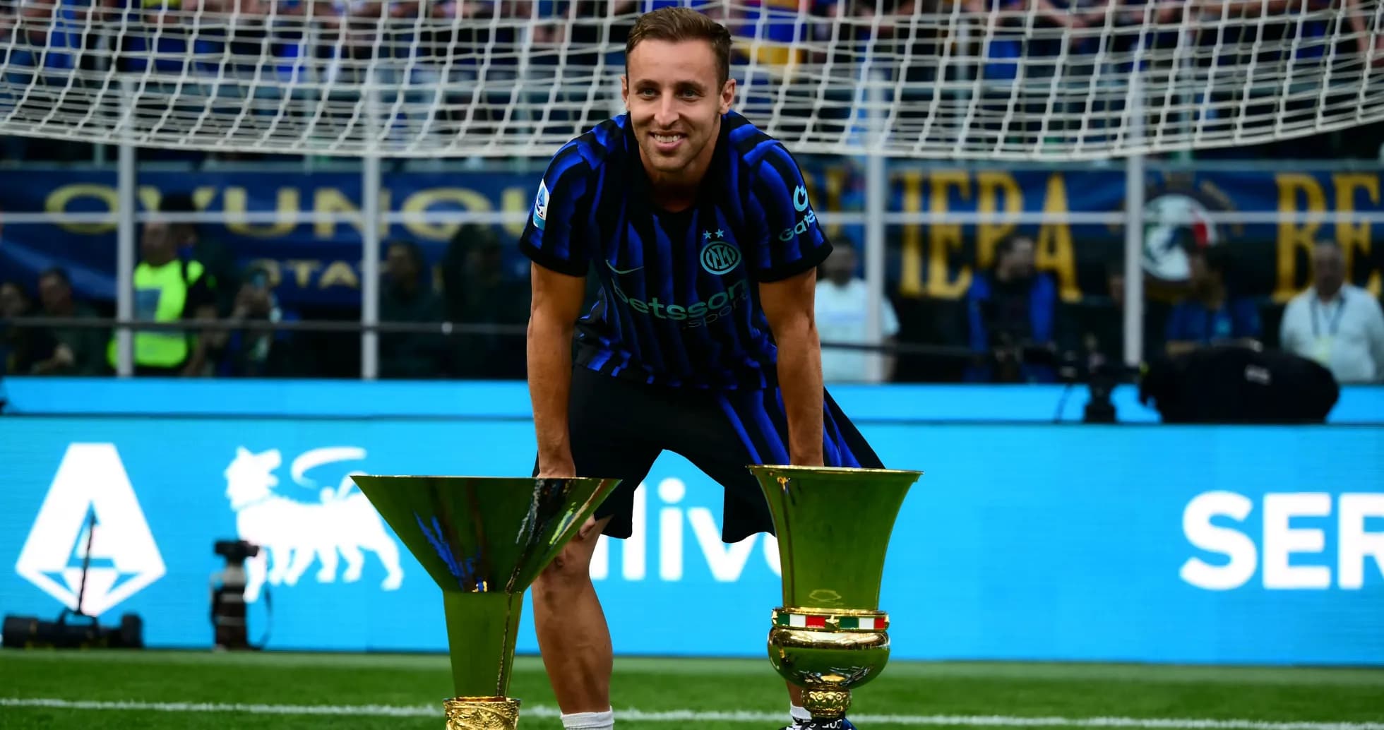 Player celebrating with two trophies on field