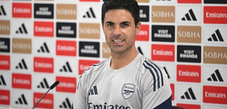 Manager speaking at press conference with Arsenal backdrop