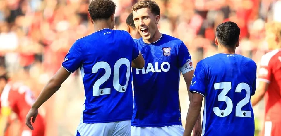 Three players celebrating on the pitch during match