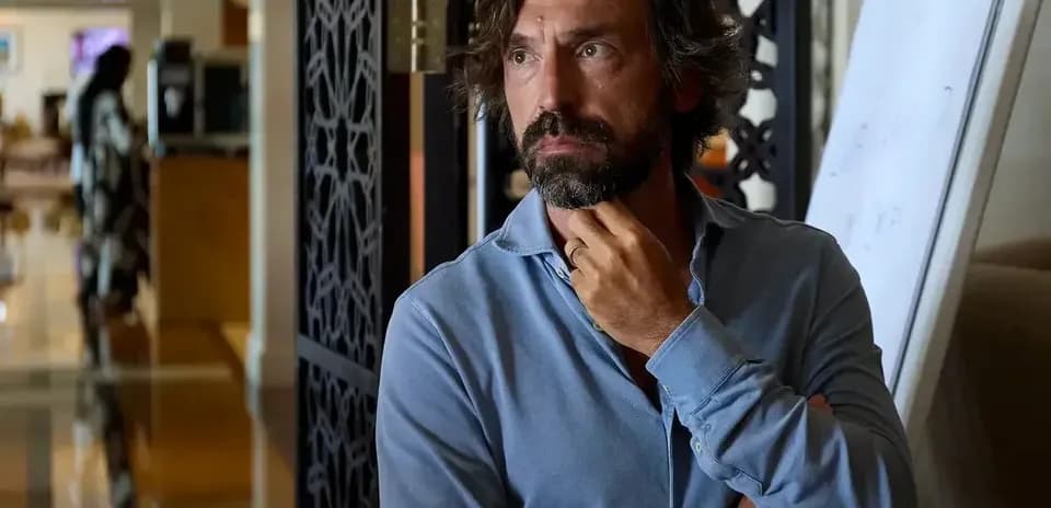Man in a blue shirt standing thoughtfully indoors