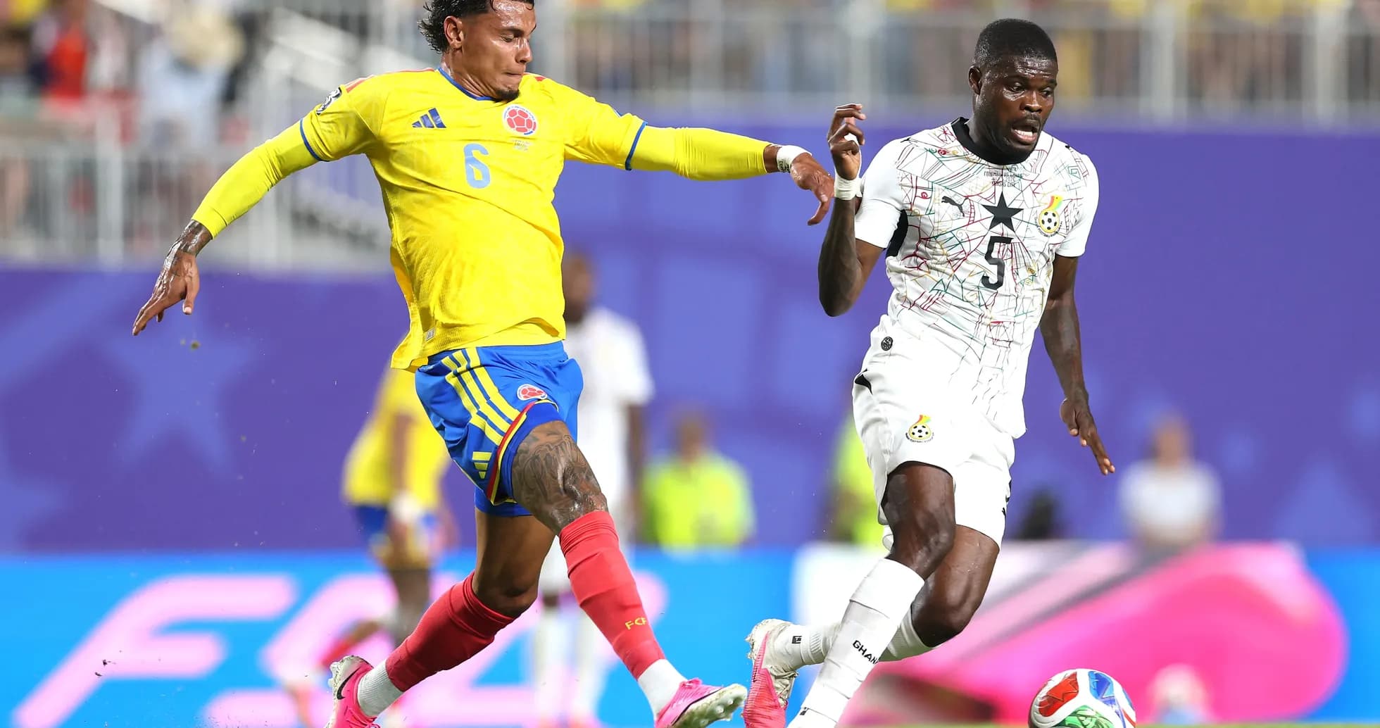 Colombia player challenges Ghana opponent for the ball
