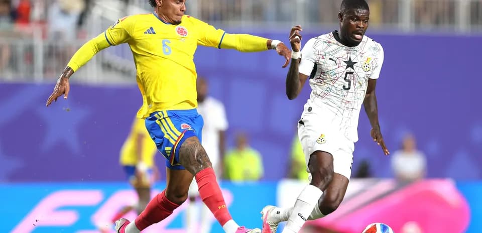 Colombia player challenges Ghana opponent for the ball