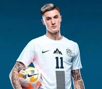 Player posing in white jersey holding soccer ball