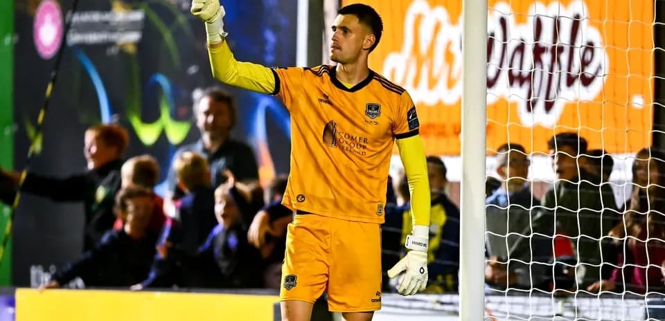 Goalkeeper signaling during a match with fans in background