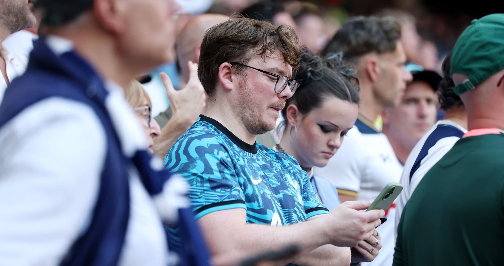Fans watching a match, focused on their phones Fans watching a match, focused on their phones